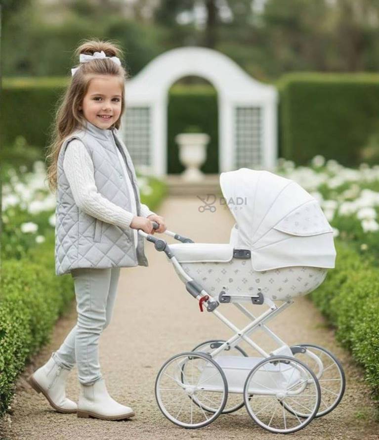 Elegancki, biały wózek dla lalek w stylu retro marki Tako Imperial Mini podczas sesji plenerowej z udziałem dziewczynki.